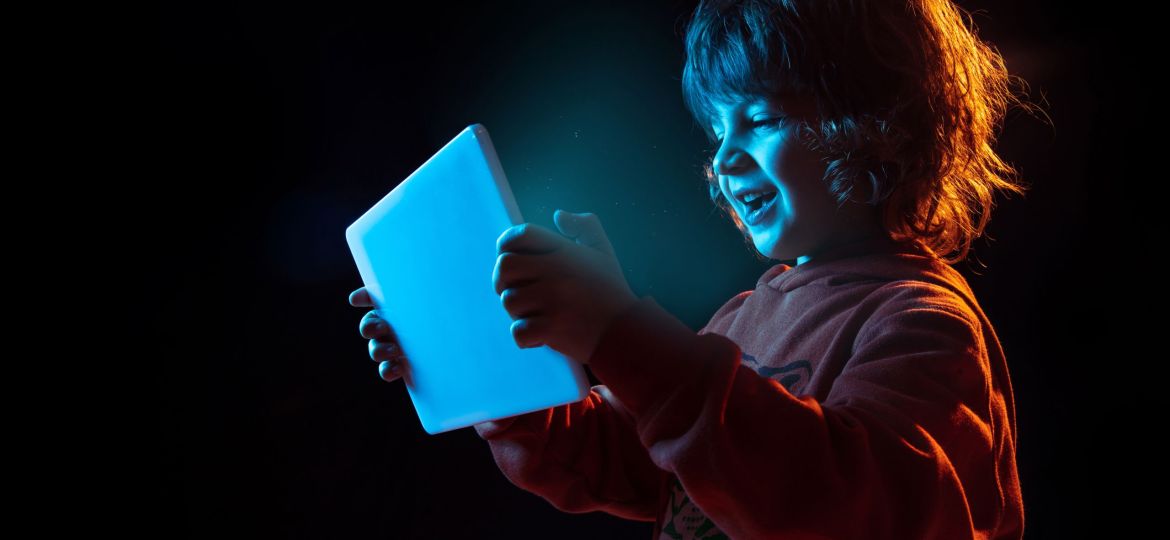 Caucasian boy's portrait isolated on dark studio background in neon light